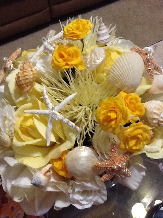 A bold beach wedding bouquet composed of white and yellow blooms, seashells and starfish