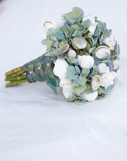 a simple greenery wedding bouquet with white seashells and mussel shells is a chic idea for a beach bride