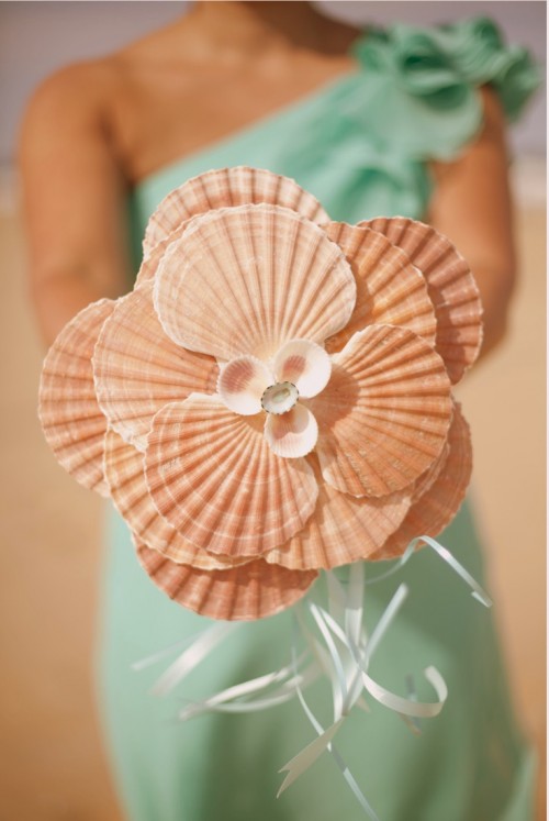 a unique beach wedding bouquet made of large seashells and some thin ribbons