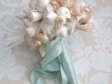 a beautiful seashell wedidng bouquet with feathers and turquoise ribbons is a chic idea for a beach wedding