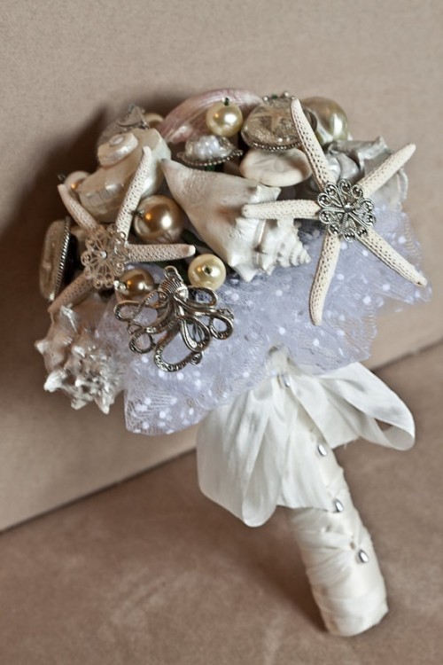 a quirky beach wedding bouquet of seashells, sea-inspired brooches, starfish and pearls plus a sequin wrap