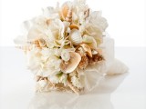 a chic neutral wedding bouquet of blooms, seashells and coral looks very cool and elegant