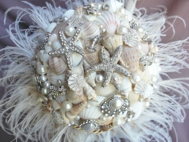 A white beach wedding bouquet of neutral shells, sparkling starfish brooches, pearls and feathers