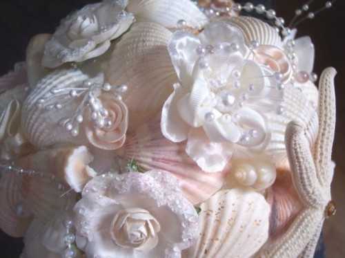 a pastel and white beach wedding bouquet of pink seashells, white seashells, pearls and fabric blooms