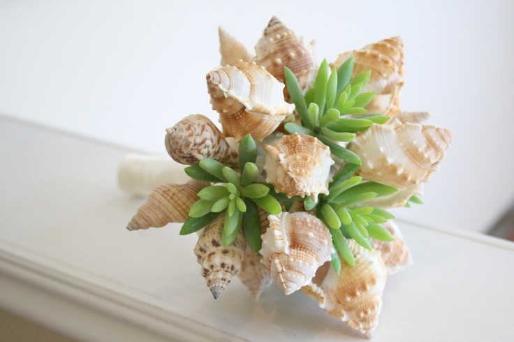A unique beach wedding bouquet of neutral shells and succulents looks very unusual