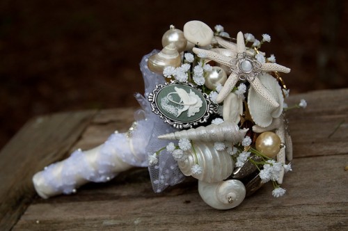 a neutrla beach wedding bouquet composed of brooches, pearls, baby's breath and ribbons