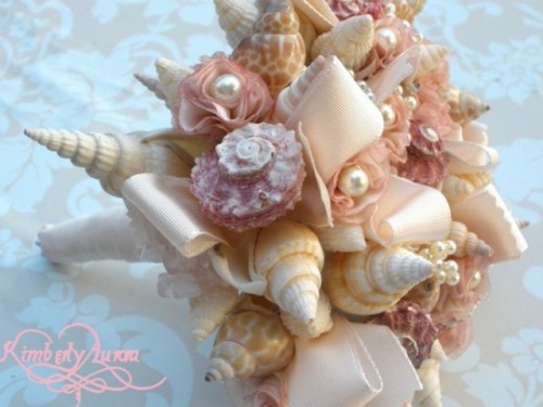 a neutral beach wedding bouquet made of seashells, neutral ribbons and fabric blooms