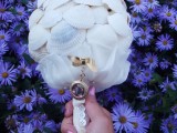 a white wedding bouquet made of seashells, white ribbon and a single photo pendant