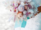 a beautiful white orchid wedding bouquet with some seashells incorporated and bright ribbons