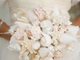 a white beach wedding bouquet made of seashells, feathers and starfish
