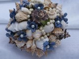 a fun beach wedding bouquet made of seashells, pearls, beads, blue fabric blooms looks unusual