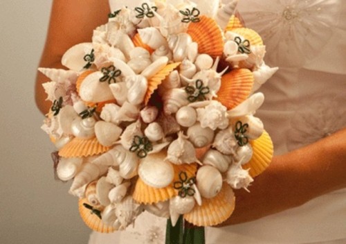 a beach wedding bouquet of yellow, neutral and mother of pearl shells plus fabric flowers