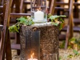 fall wedding aisle decor with a tree stump, leaves, candles and greenery on the stump and on the ground