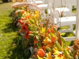 lush fall wedding aisle decor with wheat, greenery, orange tulips and yellow lilies is a gorgeous idea for the fall