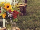 rustic fall wedding aisle decorated with stumps, jars with yellow, lilac and red blooms is a gorgoeus idea