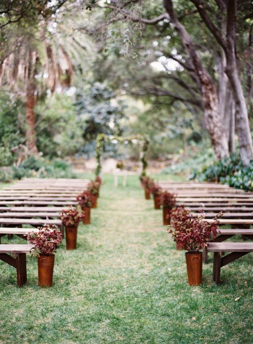 a pretty fall wedding aisle with bold leafy arrangements in copper buckets is a pretty solution for the fall
