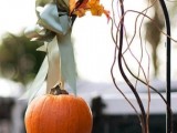 pretty fall wedding decor with a pumpkin hanging on a green ribbon, with fall leaves and twigs is a lovely idea for a rustic wedding