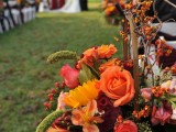 colorful fall wedding aisle styled with orange, yellow and coral blooms and lots of greenery and berries is amazing