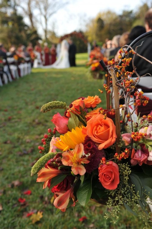 colorful fall wedding aisle styled with orange, yellow and coral blooms and lots of greenery and berries is amazing