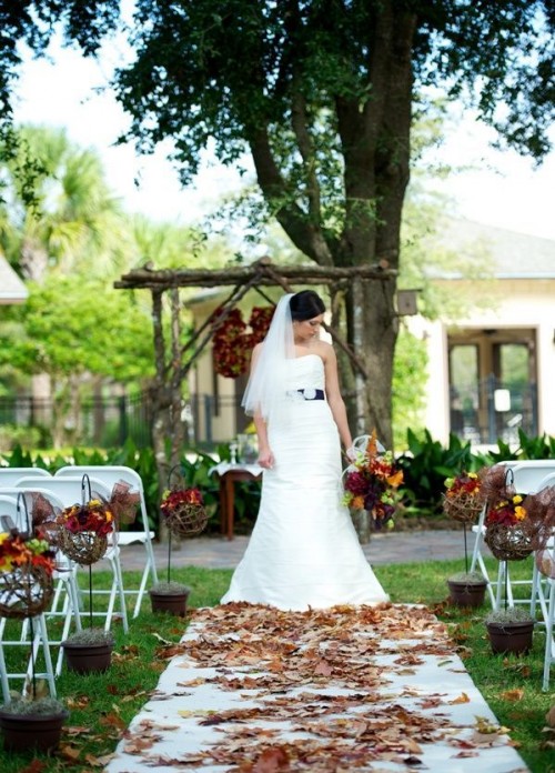 a rustic fall wedding aisle with dried fall leaves, bold blooms and a twig ball for a relaxed rustic fall wedding