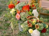 a bright rustic fall wedding aisle decor with orange, pink, yellow and white blooms and lots of greenery
