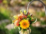 a fall wedding aisle decoration of orange and yellow blooms, with greenery and berries is a very fun and cool idea to go for