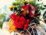 a bright floral arrangement of red and yellow blooms, greenery and berries and twigs is a very cool and bold idea for the fall