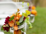 hanging jars with orange and purple blooms, greenery and berries is a lovely idea for a bright fall wedding
