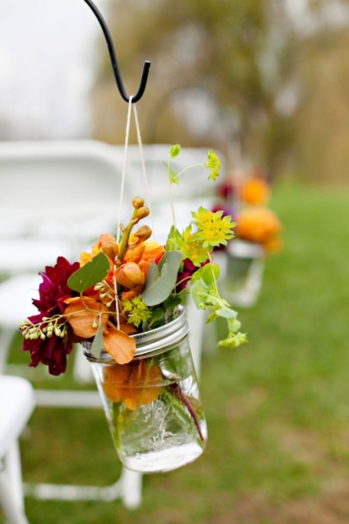 hanging jars with orange and purple blooms, greenery and berries is a lovely idea for a bright fall wedding