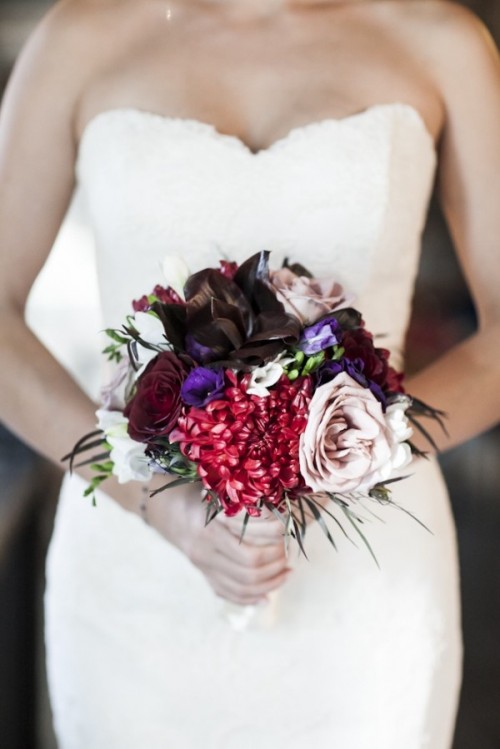 a small contrasting wedding bouquet of burgundy, black, purple and light pink blooms and greenery is a bold color statement for a colorful or moody fall wedding