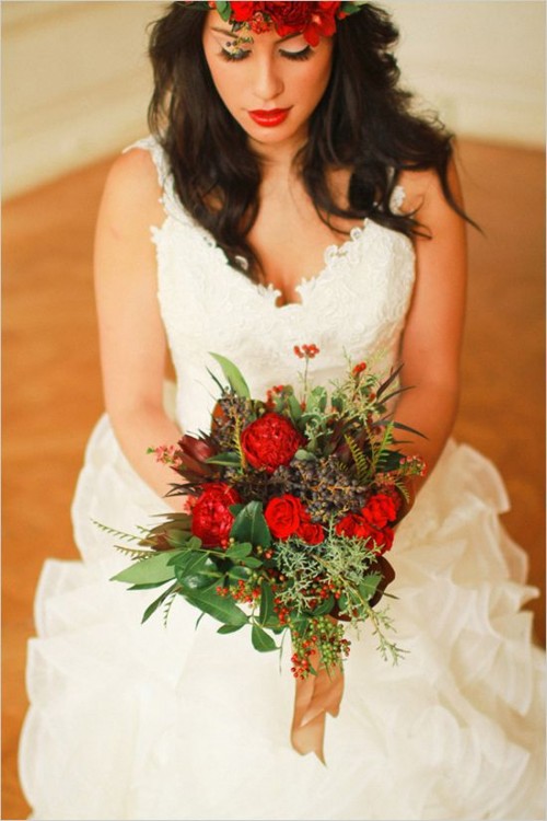 a colorful fall wedding bouquet of lots of greenery, hot red blooms, berries and some dark foliage is a veyr pretty idea for a boho bride
