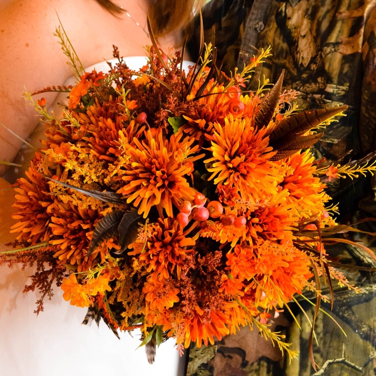 A colorful and dimensional fall wedding bouquet of orange blooms, berries and feathers plus greenery is a cool idea for a fall wedding