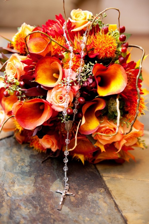 a super colorful fall wedding bouquet of orange and depe red blooms, berries, twigs is a very eye-catchy and bold solution to rock