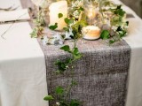 an ethereal greenery table runner combined with a grey fabric table runner and candles for a spring tablescape