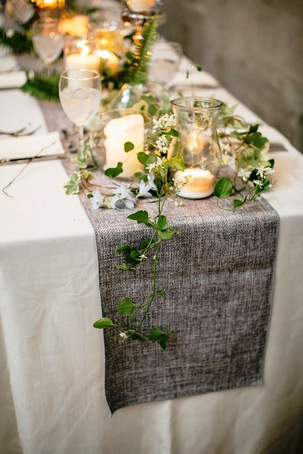 An ethereal greenery table runner combined with a grey fabric table runner and candles for a spring tablescape