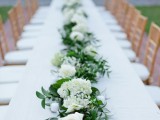 a greenery and white bloom table runner is a stylish idea for a spring wedding or a wedding with a neutral color palette