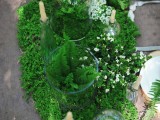 a moss and fern table runner with tiny white blooms and candles is a gorgeous idea for a woodland wedding