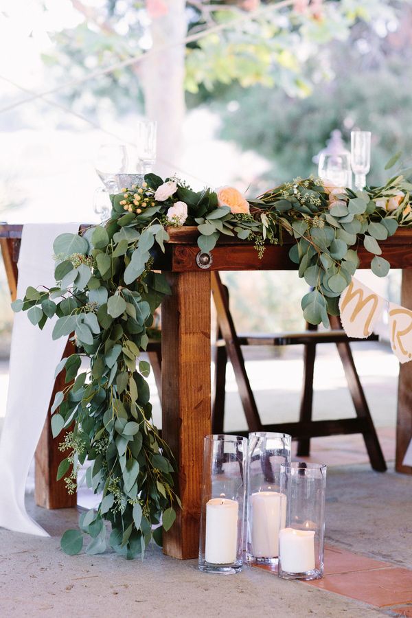 A eucalyptus table runner with peachy blooms plus candles here and there is a timeless idea