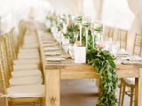 a lush greenery table runner and tall candle holders with grass for a spring table setting