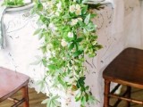 a chic greenery and white bloom table runner that covers half of the table
