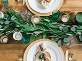 a simple fern and eucalyptus table runner and green and neutral candles for rustic tablescape