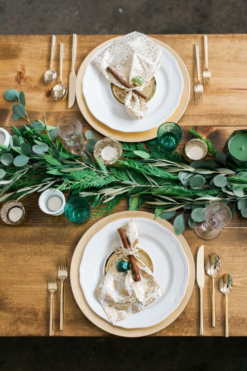 a simple fern and eucalyptus table runner and green and neutral candles for rustic tablescape