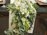 a lush eucalyptus table runner with fresh white blooms on top and a neutral table runner