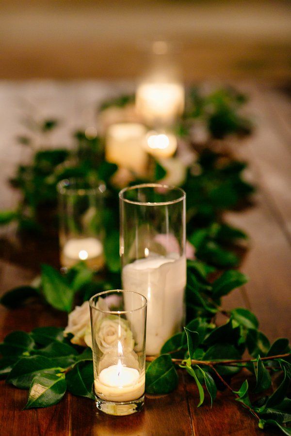 A foliage table runner, white roses, white candles to create an exquisite tablescape