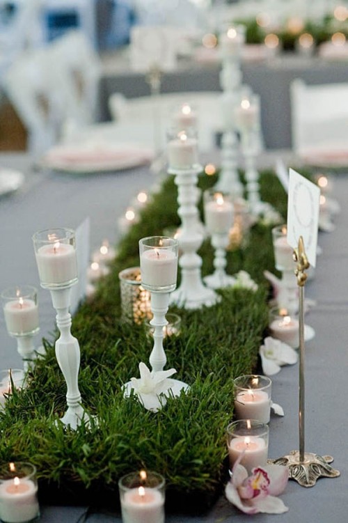 a grass table runner, white candle holders and white candles on top for a vintage feel