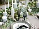 a eucalyptus table runner with concrete candle holders and tall candles for a minimalist table setting