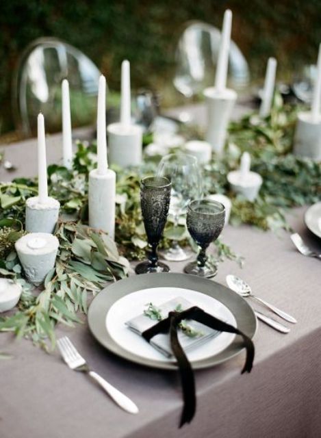 a eucalyptus table runner with concrete candle holders and tall candles for a minimalist table setting