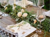 a lush foliage table runner with blush blooms on top for a fresh and chic look