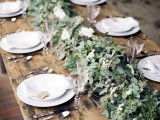 a lush and textural greenery table runner with berries is a chic idea for a winter tablescape