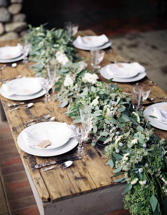 A lush and textural greenery table runner with berries is a chic idea for a winter tablescape